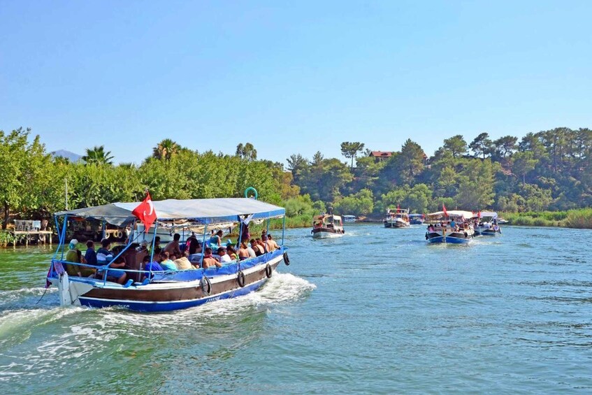 A river with boats, passengers, and a forested hillside in the background. 5