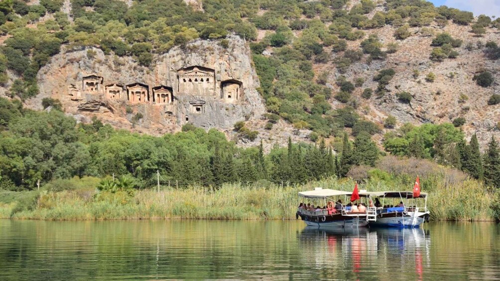 A boat on a calm river with a rocky cliff in the background featuring ancient ruins. 3