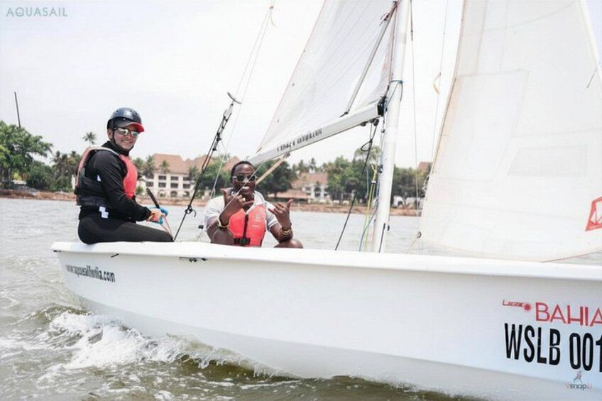Un velero con dos personas a bordo, una usando chaleco salvavidas. 1