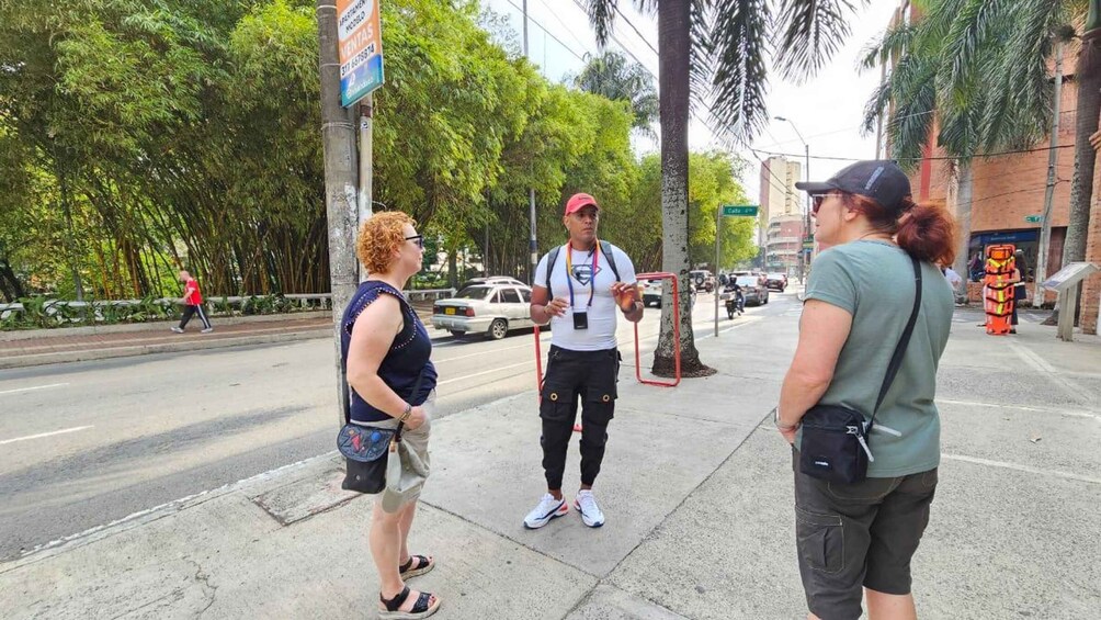 Three people on a sidewalk, a street with cars, and a building with a sign. 4