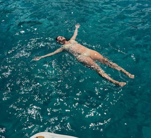 A person floating on a body of clear blue water. 4