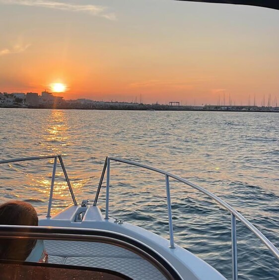 A sunset over a calm body of water with a boat in the foreground and a city skyline in the background. 5