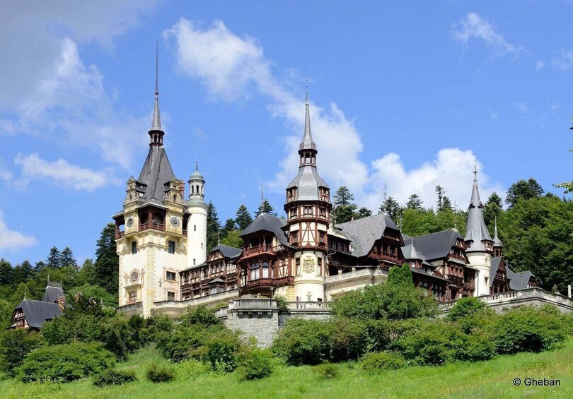 A historic castle with multiple towers, surrounded by lush greenery. 1