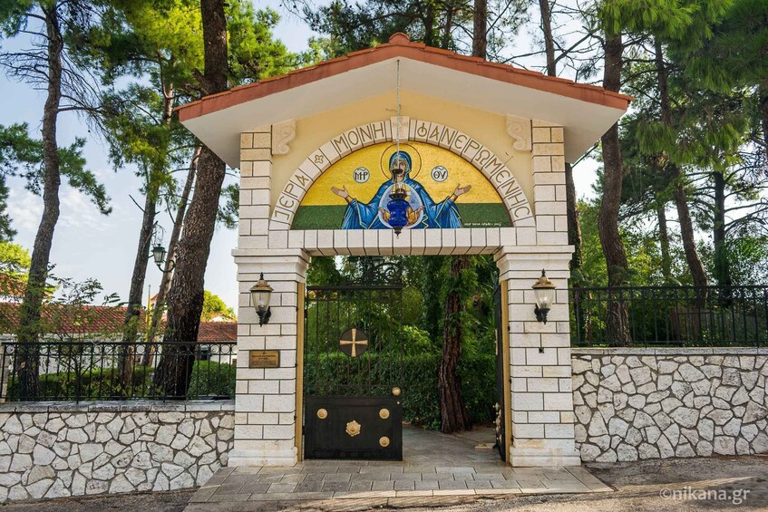 A church entrance with a cross, a blue and gold icon, and a stone wall. 4