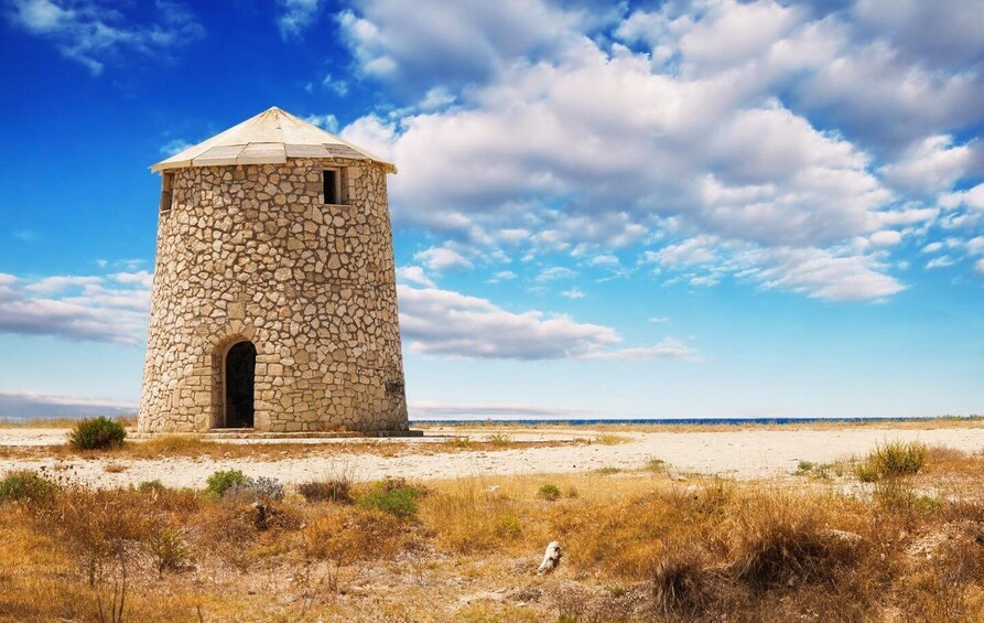 A stone tower with a conical roof on a sandy beach. 1