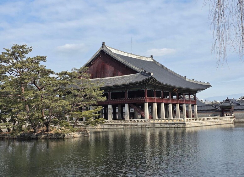 A traditional Japanese building with a tiled roof, a stone base, and a reflection in the water. 1