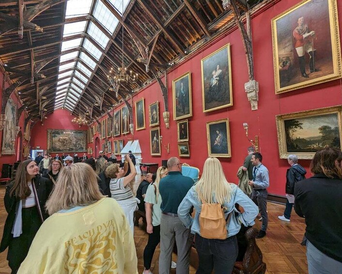 An art gallery with red walls and wooden ceilings, featuring numerous framed paintings. 3