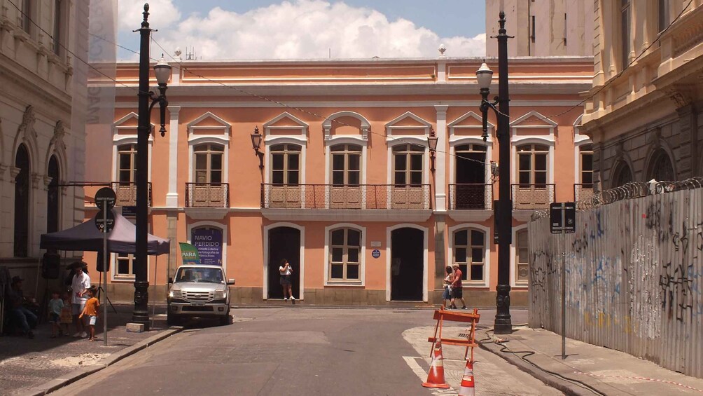 A street with a pink building, a parked car, and a construction barrier. 2