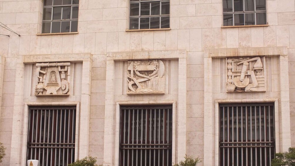 A building facade with three windows, each featuring intricate bas-relief sculptures. 3