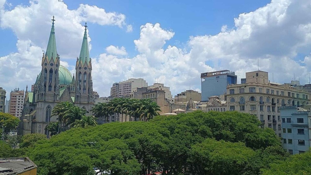 A cityscape with two prominent church spires, a mix of modern and historic buildings, and a clear blue sky. 1