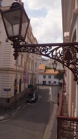 A street with a parked car, a pedestrian, and ornate street lamps. 5