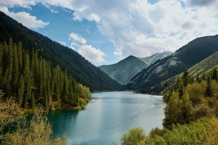 Un lago rodeado de montañas boscosas bajo un cielo parcialmente nublado. 2