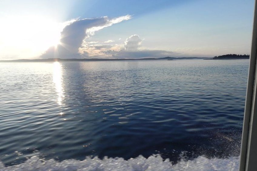 A calm sea with a boat's wake, a clear sky, and distant land. 3