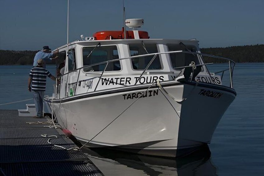 A boat named 'Water Tours' docked at a pier with a person standing on the deck. 1