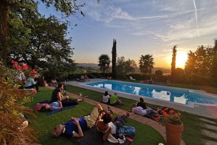 People relaxing by a pool with a sunset in the background. 5