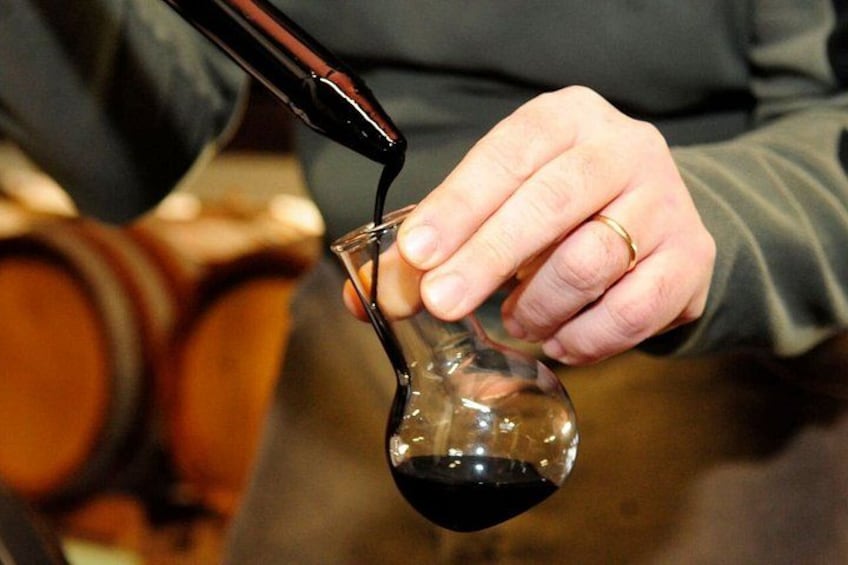 A person pouring red liquid from a bottle into a glass. 1