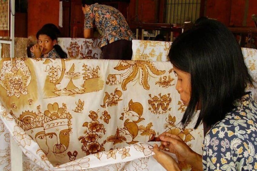 A person sitting at a table with a tablecloth featuring traditional patterns. 3