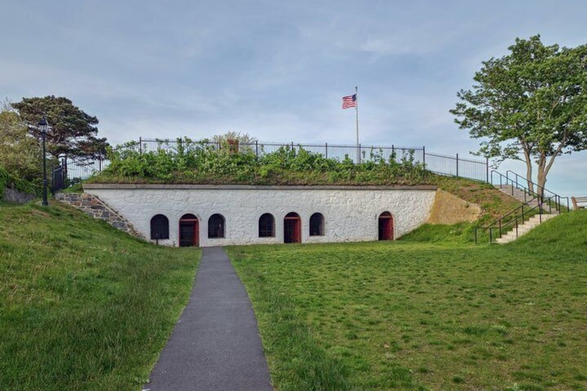 A stone building with arched doorways, a flag, and a pathway leading to it. 2