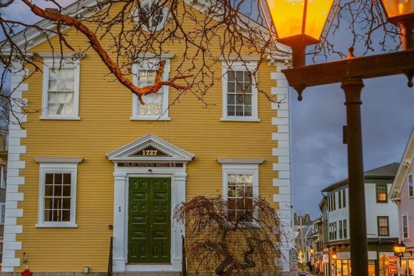 A yellow building with a green door and the number 1727, a street lamp, and bare trees. 4
