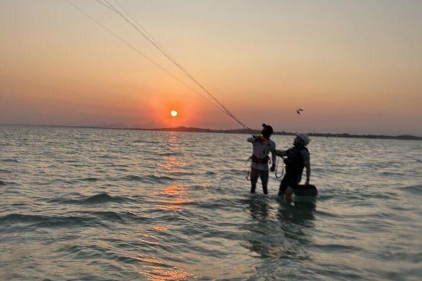Two people fishing at sunset with the sun visible on the horizon. 2
