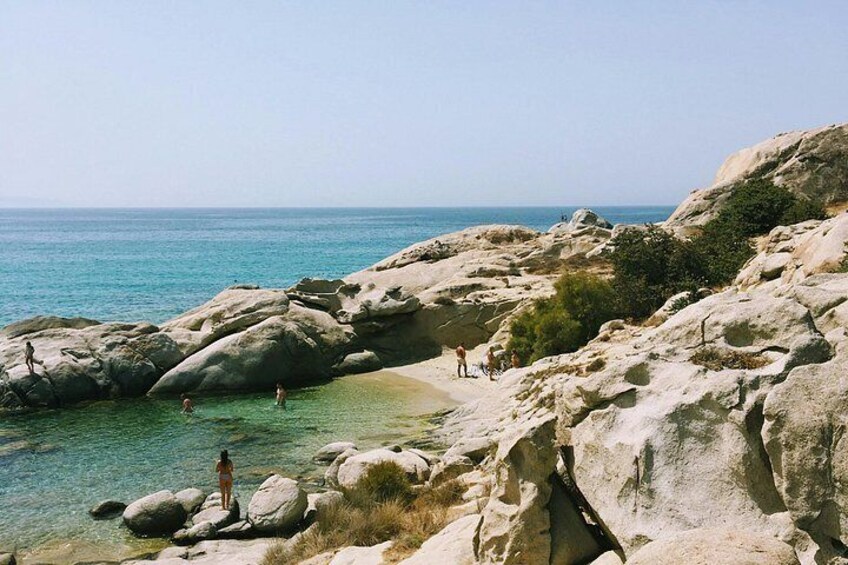 A rocky coastline with clear water, people swimming, and a clear sky. 4