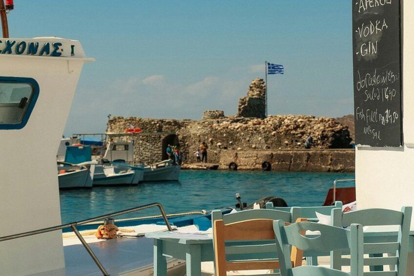 A coastal scene with boats docked, a stone wall, and a flag. 1