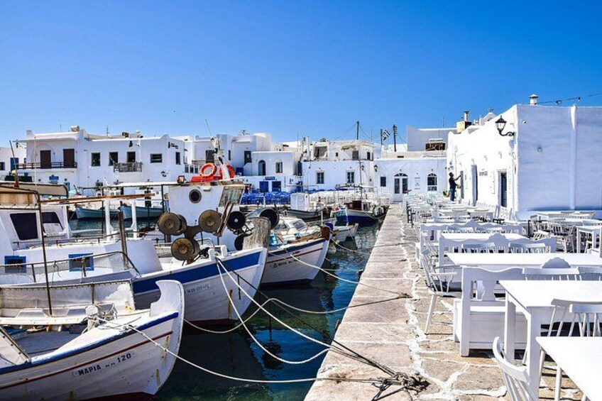 A harbor with boats docked, white buildings, and a clear blue sky. 3