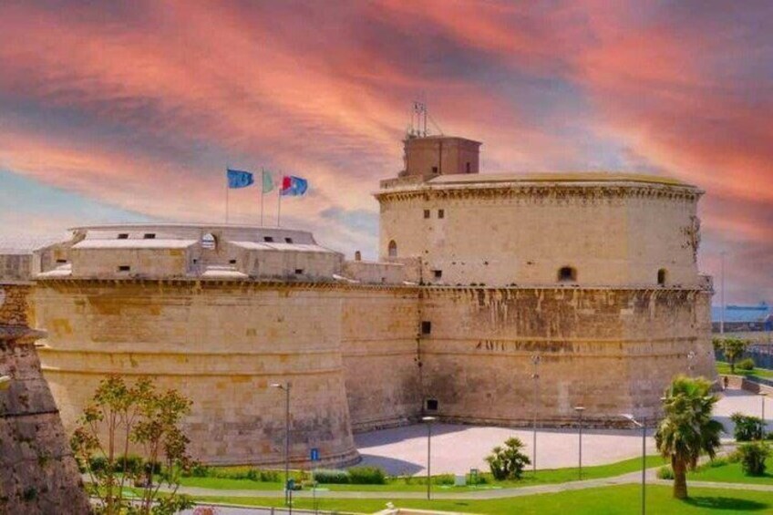 Ett historiskt fort med flaggor, ett runt torn och ett grönskande landskap runt omkring. 5