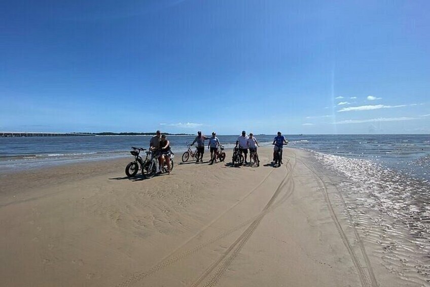 A beach with people on bicycles and a clear sky. 4