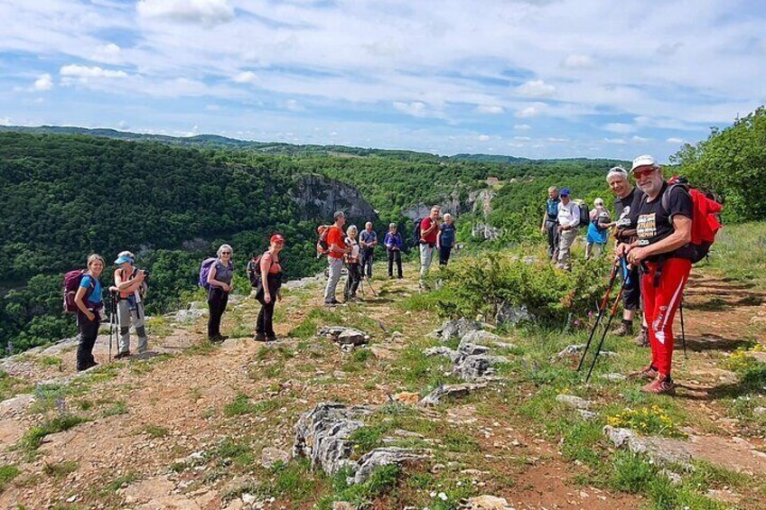 A group of hikers on a mountain trail with rocky terrain and green vegetation. 5
