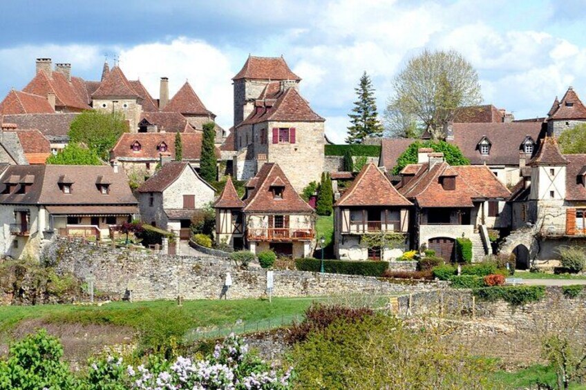 A historic village with stone buildings, a church, and a stone wall. 1
