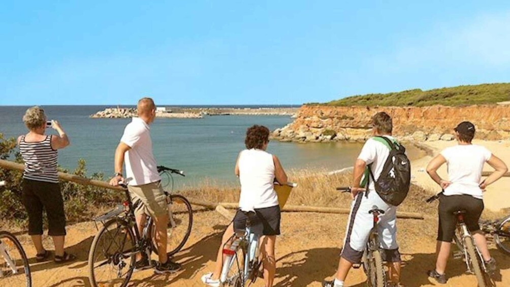 A group of people on bicycles by a coastal area with a clear sky. 3