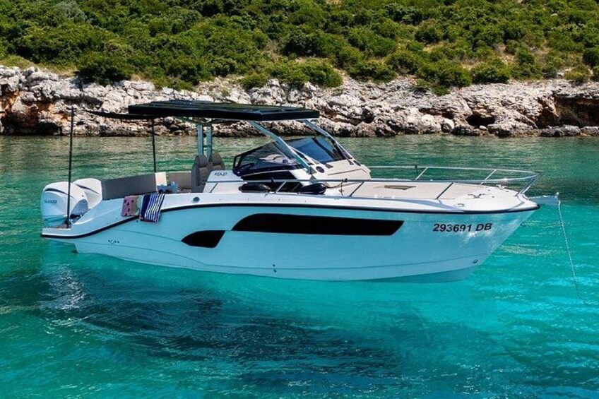 A white motorboat with the registration number 293691 DB on clear turquoise water. 1