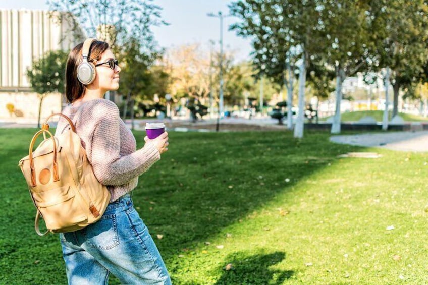 Une personne marchant sur l’herbe, portant un sac à dos et tenant une tasse. 5