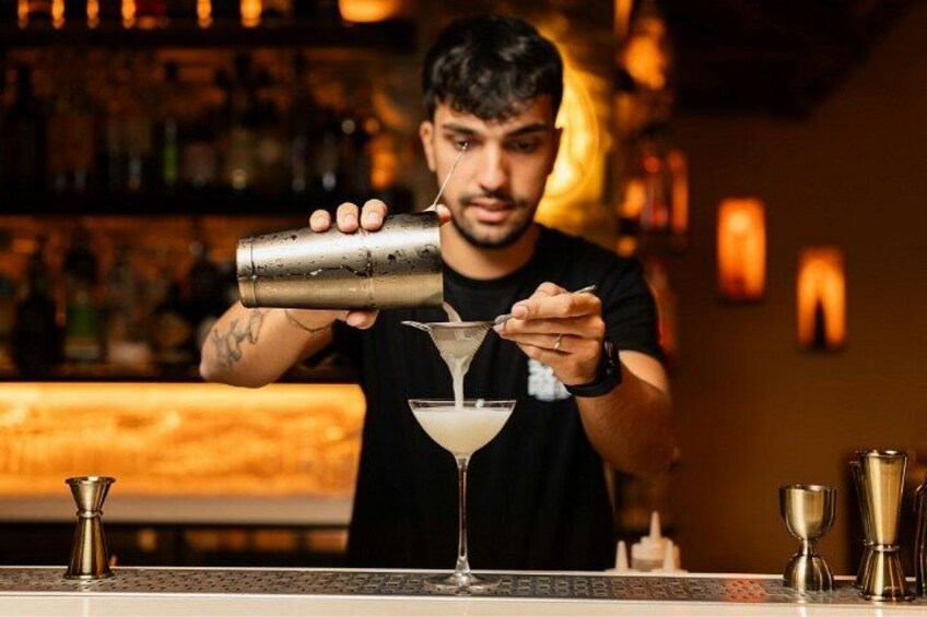 Un barista versa un drink in un bicchiere da martini. 3