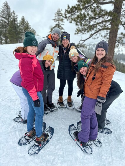 A group of people snowshoeing on a snowy slope with trees in the background. 2
