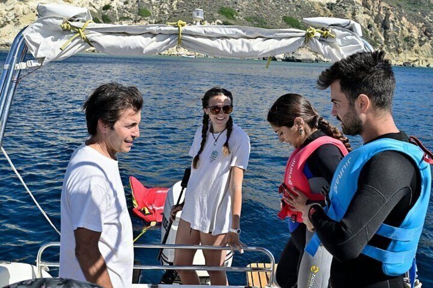 A group of people on a boat with a rocky shoreline in the background. 4