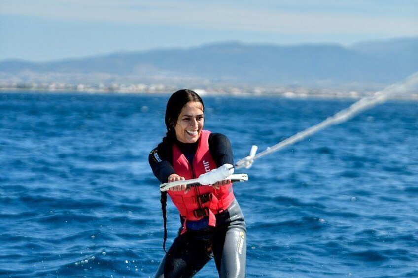 A person water skiing on a body of water with a coastline in the background. 1