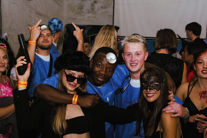 Un grupo de personas en un evento social, algunas con mascarillas y otras con bandanas. 4