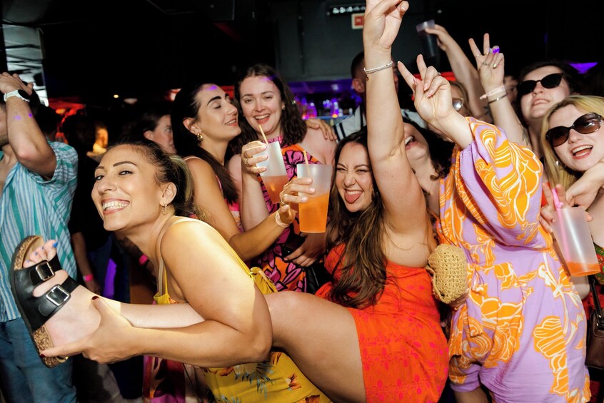 Un grupo de personas bailando y sosteniendo bebidas en una fiesta. 1