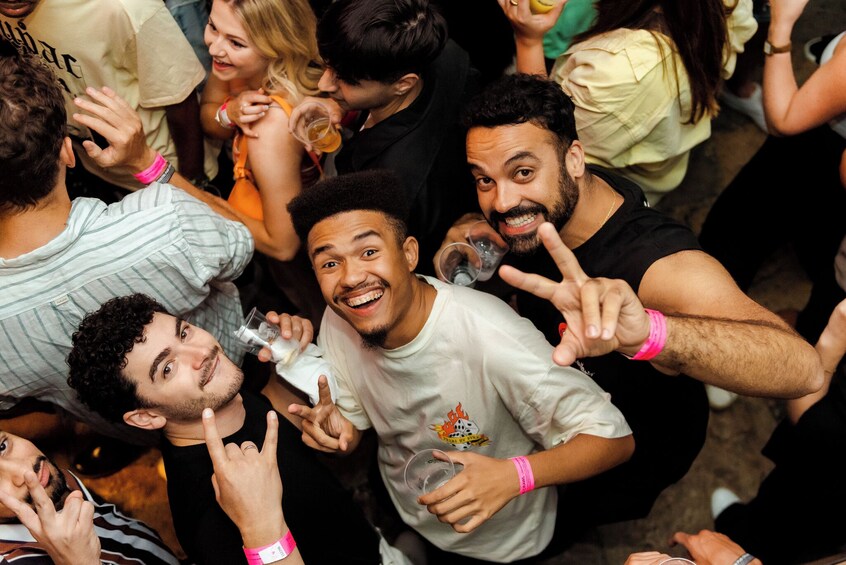 Un grupo de personas en un evento social, algunas sosteniendo bebidas y gesticulando. 2