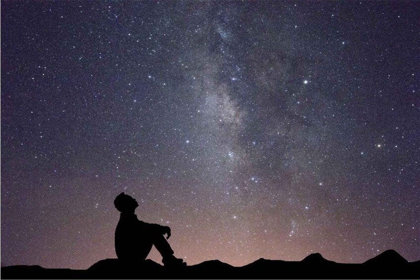 A silhouette of a person gazing at a starry night sky with the Milky Way visible. 3
