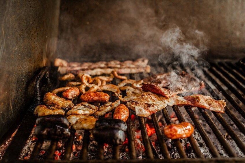 A grill with various meats cooking over an open flame. 5