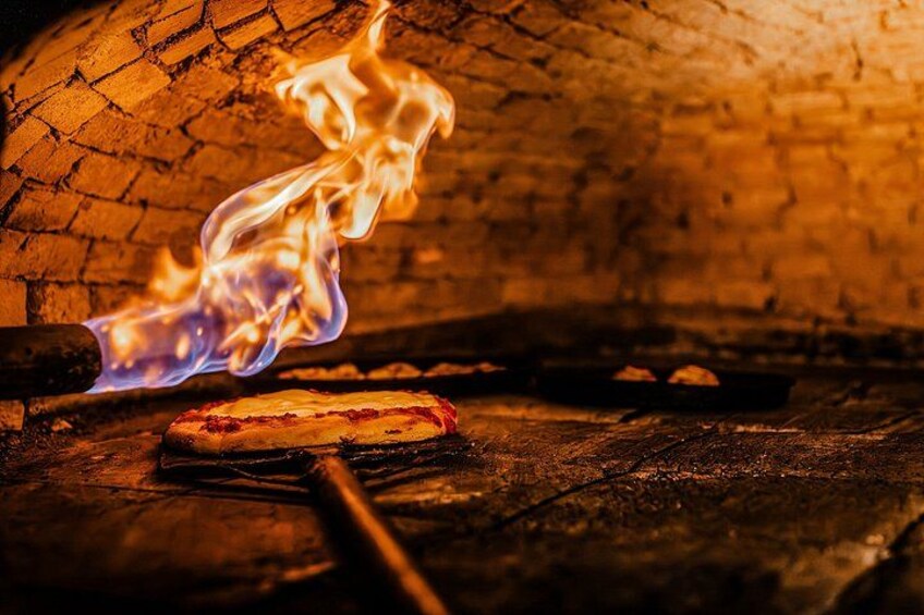 A pizza in a brick oven with flames. 1