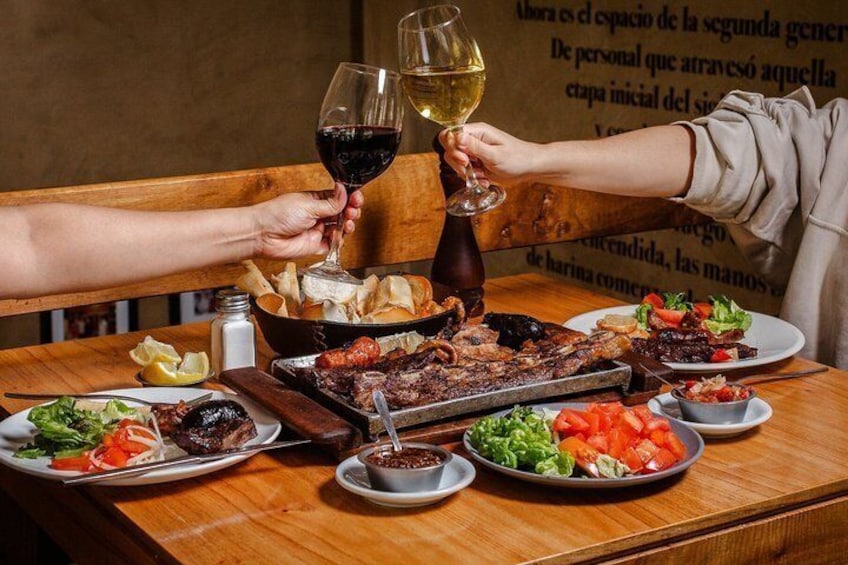 Une table en bois sur laquelle on trouve divers plats, notamment de la viande grillée, des salades et du pain. 3