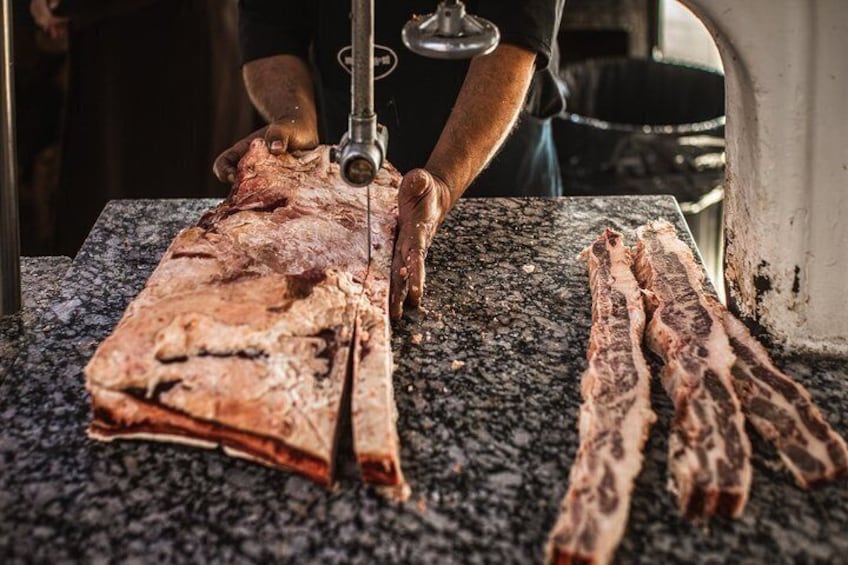 Une personne est en train de découper une grande pièce de viande sur un plan de travail en granit. 5