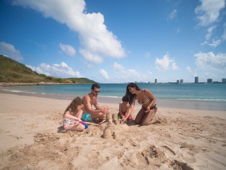 A family building a sandcastle on a beach with a city skyline in the background. 3
