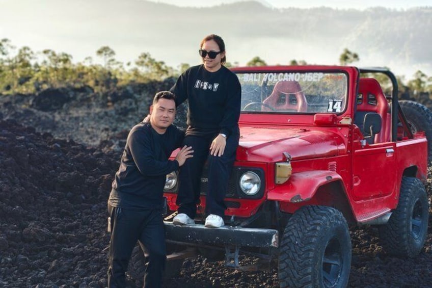 Twee personen staan naast een rood terreinvoertuig, op de voorruit staat 'BALI VOLCANO JEEP' geschreven. 5