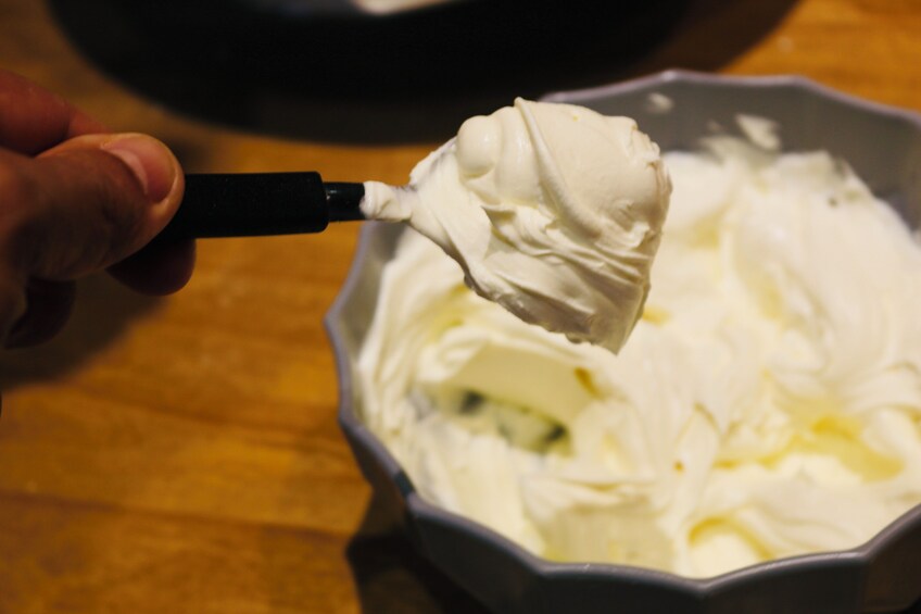A hand holding a spatula scooping whipped cream from a bowl. 5