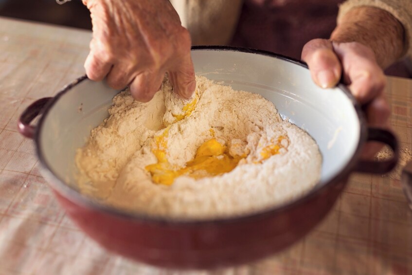 A person mixing ingredients in a bowl. 2